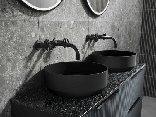 Black Bathroom Basin, with black wall mounted basin taps, black round illuminated mirrors on grey tiles and black basin vanity units