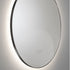 Round wall mirror with a light fixture on a gray background