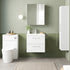 Bathroom setup with white vanity, toilet, and cabinet against a green tiled wall.