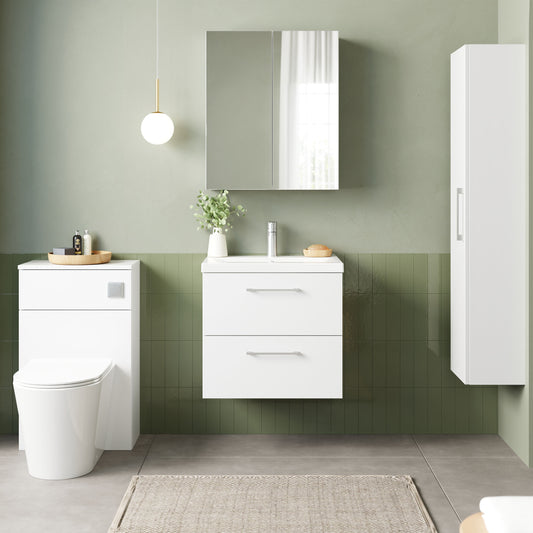 Bathroom setup with white vanity, toilet, and cabinet against a green tiled wall.