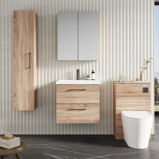 Bathroom setup with wooden cabinets, a sink, and a toilet against a tiled wall.