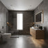 Modern bathroom interior with dark gray stone-look tiles, a floating wood vanity with a white basin, a wall-mounted toilet, a glass shower enclosure, and a large backlit mirror.