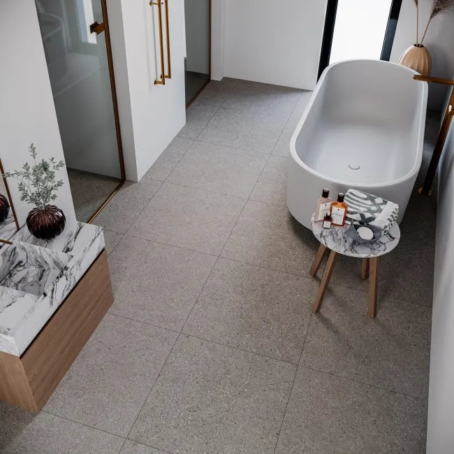 Modern bathroom with a freestanding bathtub, marble countertop, and small table.