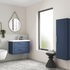 Bathroom interior with blue vanity unit, mirror, and storage cabinet.
