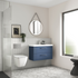 Bathroom interior with blue vanity unit, white toilet, and round mirror.