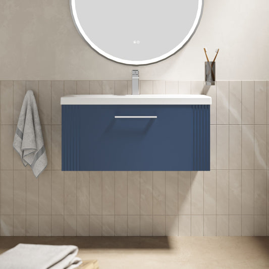 Bathroom vanity with blue cabinet, white countertop, and round mirror on beige tiled wall.