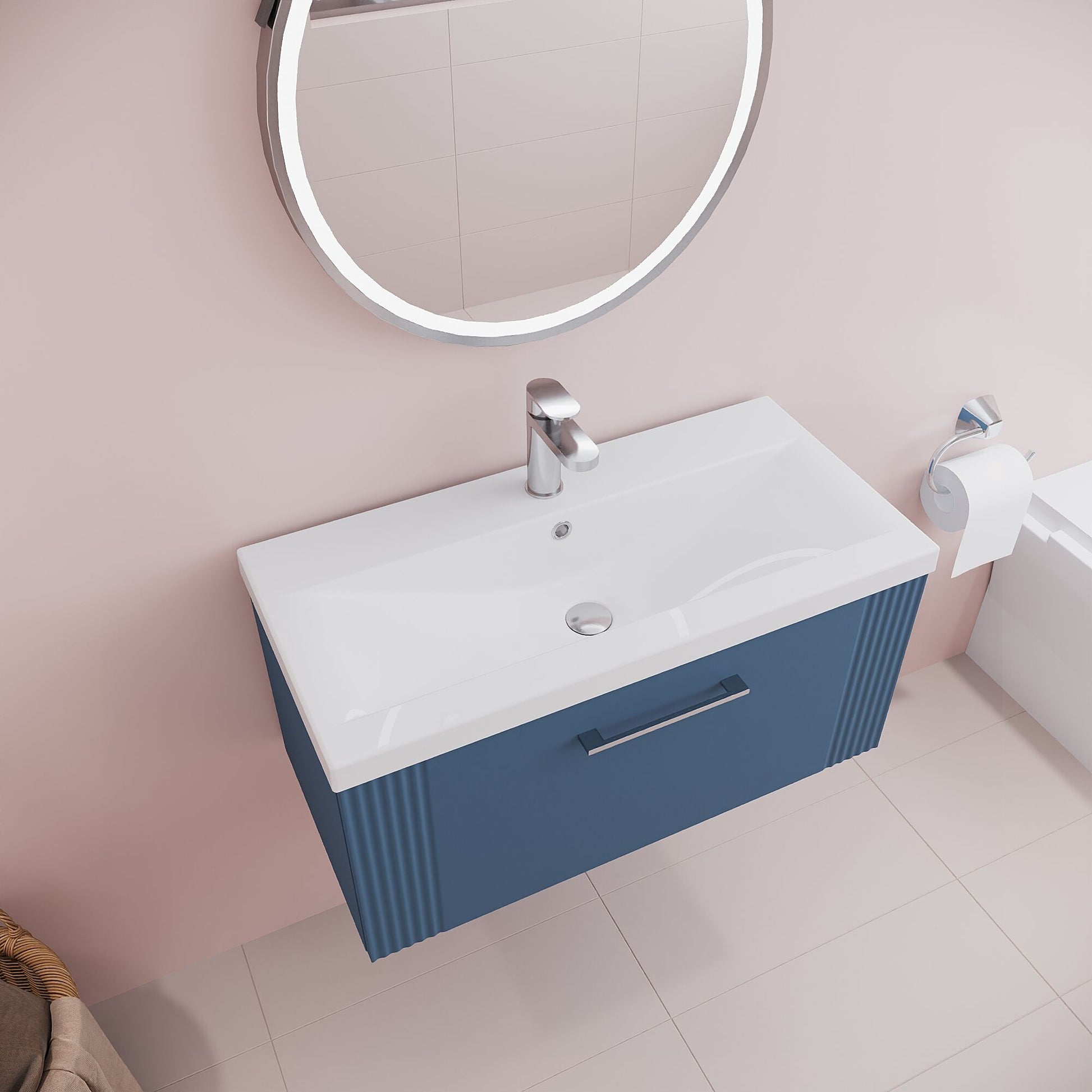 Bathroom vanity with blue cabinet, white countertop, and round mirror on a light pink wall.