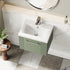 Bathroom vanity with white sink and green cabinet, featuring a round mirror above.