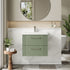 Bathroom vanity with green cabinet, white countertop, and round mirror.