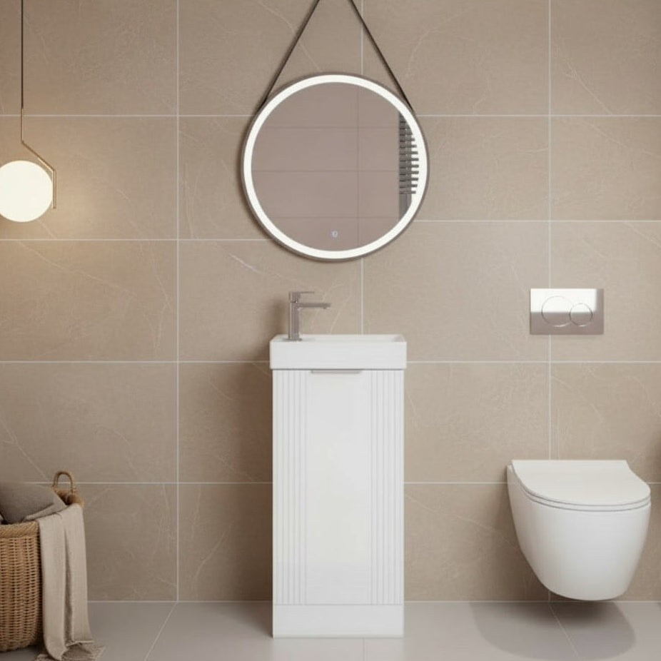 Modern bathroom with beige tiles, a round mirror, sink, and toilet.