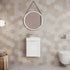 Bathroom with hexagonal tile pattern, round mirror, and white vanity.