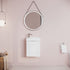 Bathroom with round mirror and white vanity against a pink wall