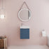 Bathroom with blue vanity unit, round mirror, and pink wall.