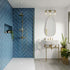 Modern bathroom with blue tiled wall, marble vanity, and gold fixtures. Multipanel Misty Blue Herringbone Tile Effect Wet Wall Shower Panel