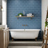 Bathroom with blue tiled wall, white bathtub, and wooden shelves. Multipanel Misty Blue Metro Tile Effect Wet Wall Shower Panel