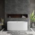 An oval-shaped, white freestanding bathtub with a textured exterior, positioned against a dark tiled wall with a wooden shelf above it. The bathtub is designed for adults and features a central drain.