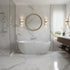 Modern bathroom with marble walls, a freestanding bathtub, and a round mirror.