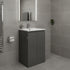 Bathroom with gray tiled walls and floor, featuring a black vanity unit with white sink.