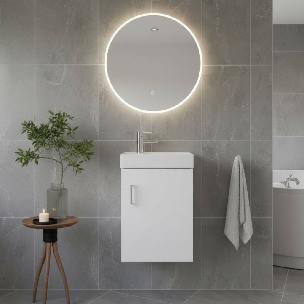 Modern bathroom with round illuminated mirror, white vanity, and gray tiles.