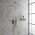 Gold shower system mounted on a fluted marble grey tiled wall with a glass partition.