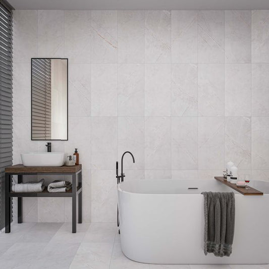 Modern bathroom with a freestanding bathtub, sink, and mirror and marble wall tiles