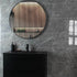 Bathroom with round mirror, black vanity, and grey marble wall tiles.