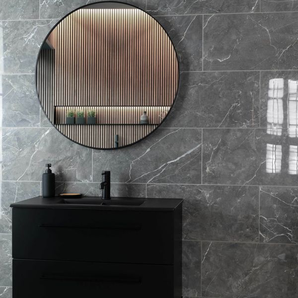 Bathroom with round mirror, black vanity, and grey marble wall tiles.