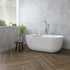 Modern bathroom with a freestanding bathtub against a fluted marble tiled wall.