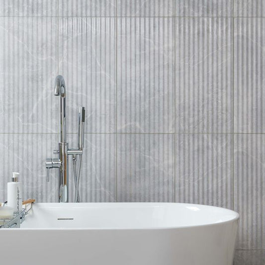 Bathroom with a freestanding bathtub against a marble fluted tiled wall
