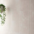 Beige textured wall tiles with a hanging plant on the left side
