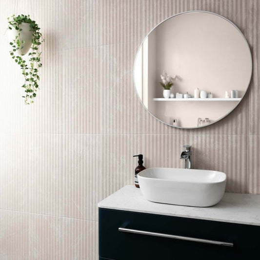 Modern bathroom with marble fluted tiled wall, round mirror, sink, and decorative elements.