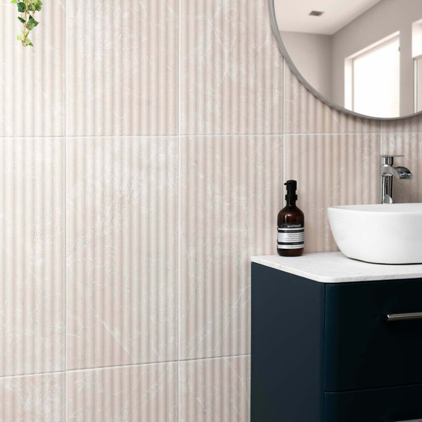 Bathroom with fluted marble tiled wall, sink, and decorative bottle.