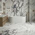 Modern bathroom with marble walls and floor, fluted freestanding bathtub, and gold fixtures.