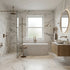 Modern bathroom with marble walls and floor, fluted freestanding bathtub, and wooden vanity.