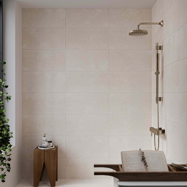 Modern bathroom with warm white tiled walls, shower head, and wooden stool.