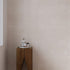 Bathroom corner with warm white stone effect tiled walls and a wooden cabinet with toiletries.