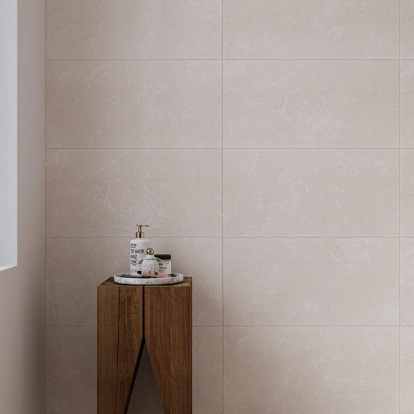 Bathroom corner with warm white stone effect tiled walls and a wooden cabinet with toiletries.