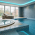 Indoor pool area with tiled floor and wall, lounge chair, and large windows.