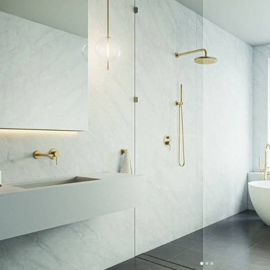 Modern bathroom with white tiles, a freestanding bathtub, and gold fixtures.