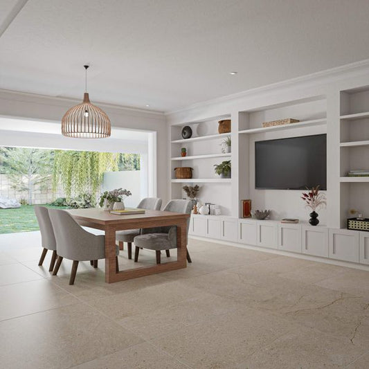 Modern living room with beige stone floor tiles, a wooden dining table and chairs, white shelves, and a TV.