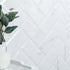White marble tiles with a marble subway geometric pattern and a white vase with green leaves.