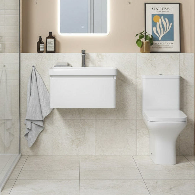Bathroom with white vanity and toilet against a tiled wall.