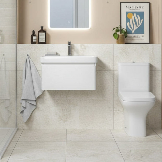 Bathroom with white vanity and toilet against a tiled wall.